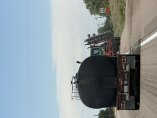 Farm machine ahead of a tanker on the highway
