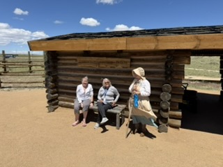 Two pioneers on the brand-new bench outside the log cabin